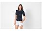 Frau in einem marineblauen gerippten Poloshirt und weißen Shorts, lächelnd in die Kamera.
