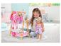 Mädchen spielt mit BABY born Puppe und Kleiderständer mit Puppenkleidung.