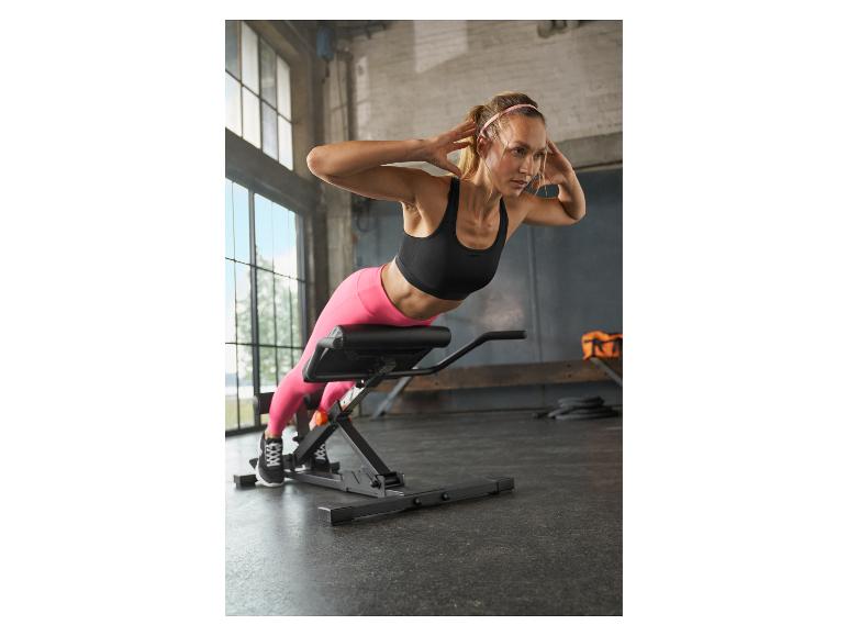 Frau auf einer Hyperextensionsbank, die eine Rückenübung in einem Fitnessstudio macht.