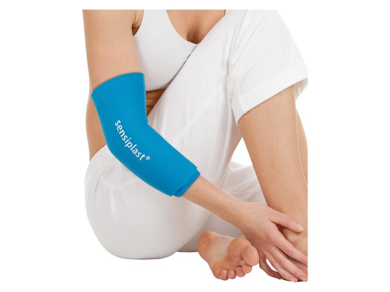 Frau in Weiß sitzend, mit blauer Ellbogenbandage mit Text am Arm.
