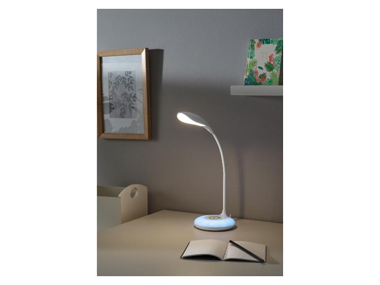 Weiße Schreibtischlampe mit leuchtender Basis, auf einem Schreibtisch mit einem Notizbuch.