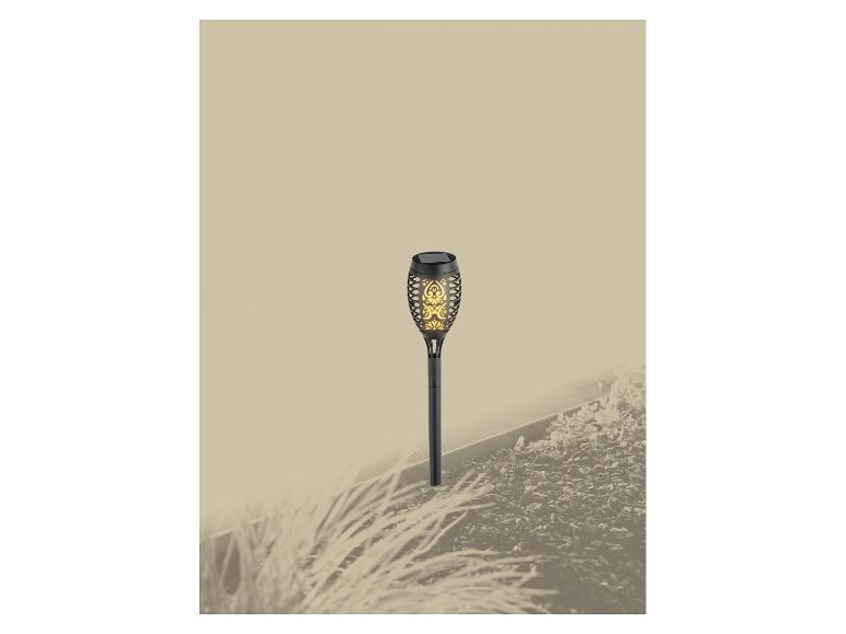 Solar-Gartenleuchte mit Flammeneffekt in einem Blumenbeet.