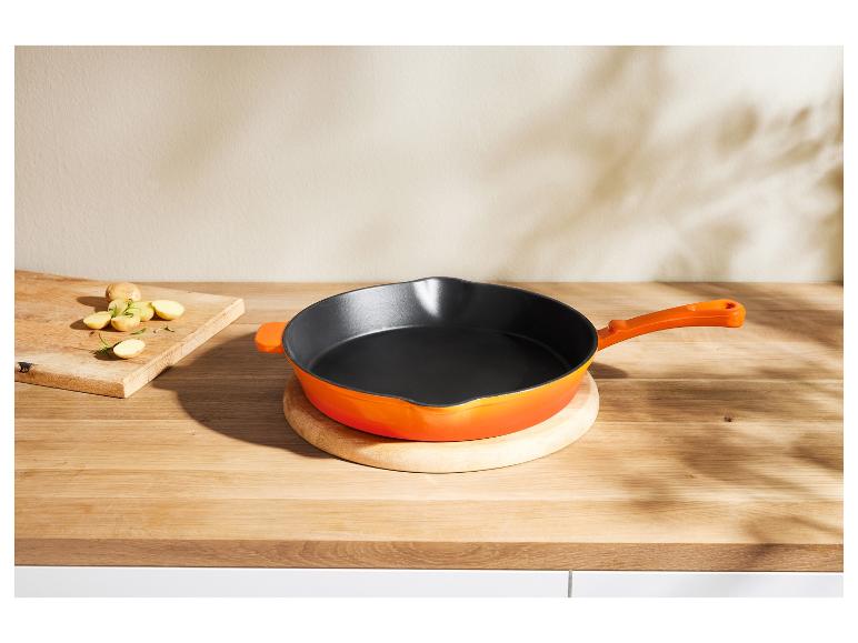 Eine orange Le Creuset Pfanne auf einer Holztheke.