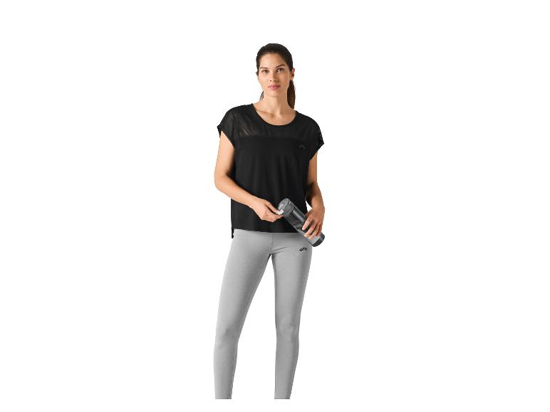 Frau in schwarzem Top und grauen Leggings, hält eine Wasserflasche.