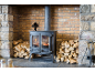 Holzofen mit brennendem Feuer, Holzstapeln und Kaminbesteck.