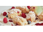 Donuts mit Puderzucker und Streuseln bestreut, mit Himbeeren und Blaubeeren.