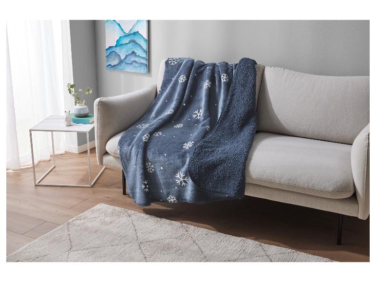 Blaue Schneeflocken-Decke auf einem beigen Sofa in einem modernen Wohnzimmer.