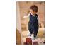 Baby in blauem Schlafsack mit Sternen, spielt in einem Zimmer.