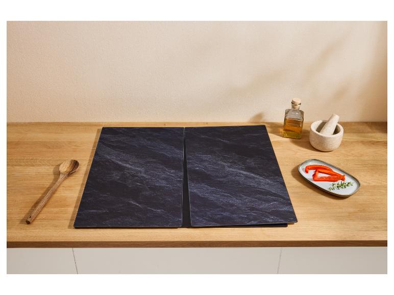 Cerankochfeldabdeckungen mit Küchenutensilien und Zutaten auf einer Holzarbeitsplatte.