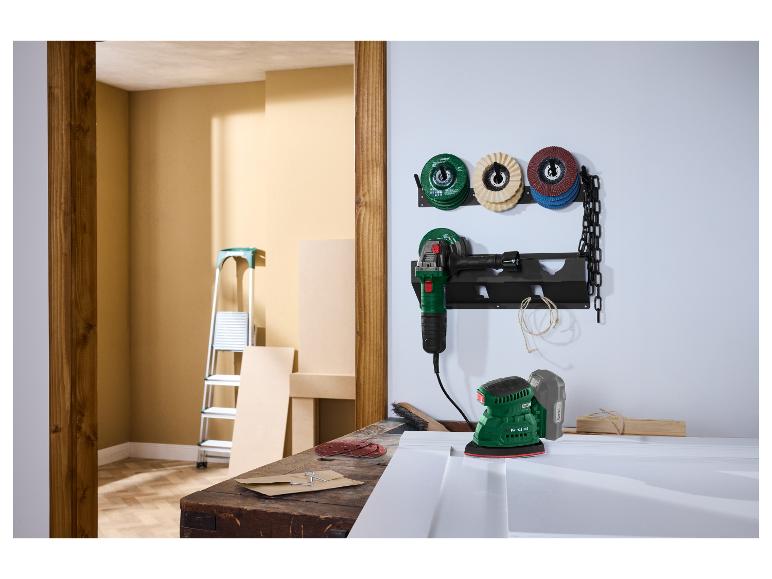 Eine Werkstattszene mit einem Winkelschleifer und einem Schleifer auf einer Werkbank, mit Schleifscheiben an der Wand.