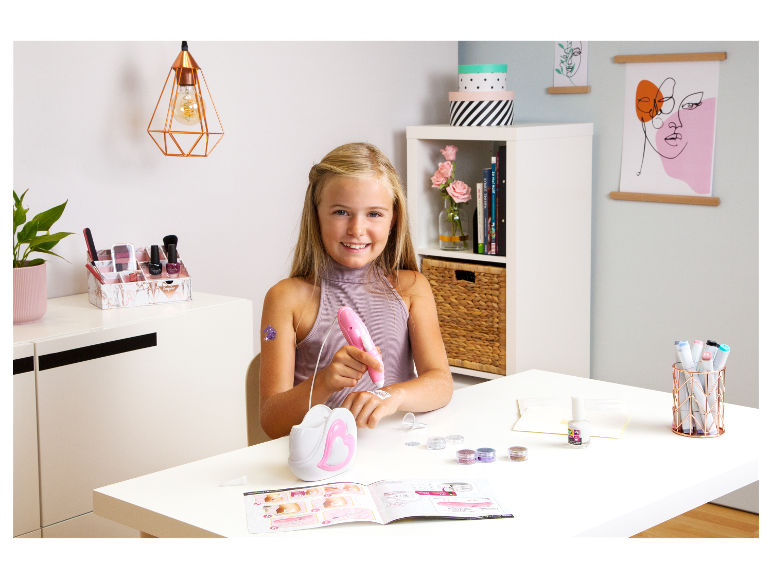 Mädchen benutzt eine Glitzerpistole, um temporäre Tattoos zu erstellen.