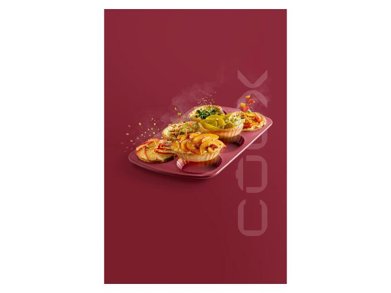 Vier kleine Tartelettes in einer Backform auf rotem Hintergrund.