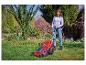 Frau mäht den Rasen mit einem roten Rasenmäher im Garten.