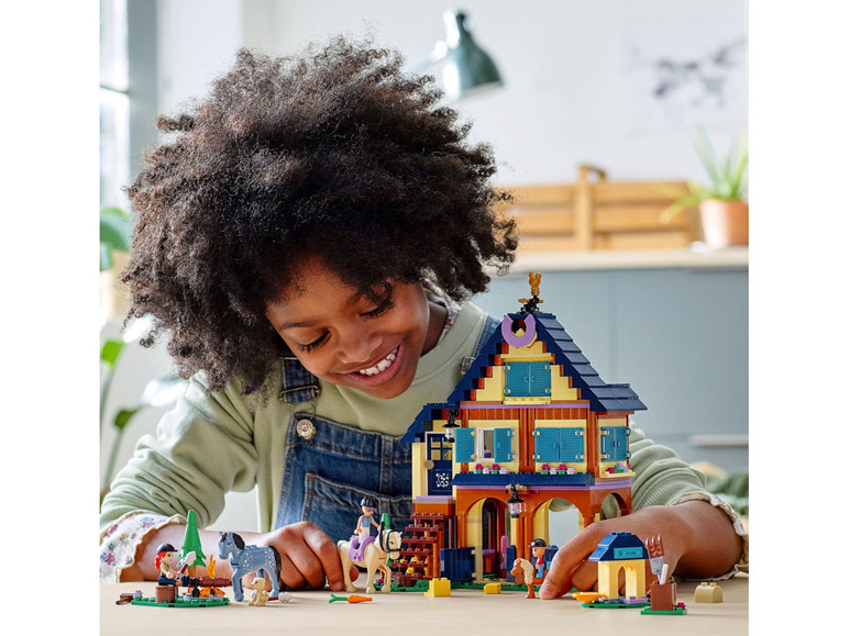 Ein Kind spielt mit einem LEGO Friends Pferdestall mit Pferden und Zubehör.