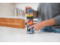 Person bereitet Smoothie in einem tragbaren Mixer mit Obst und Gemüse zu.