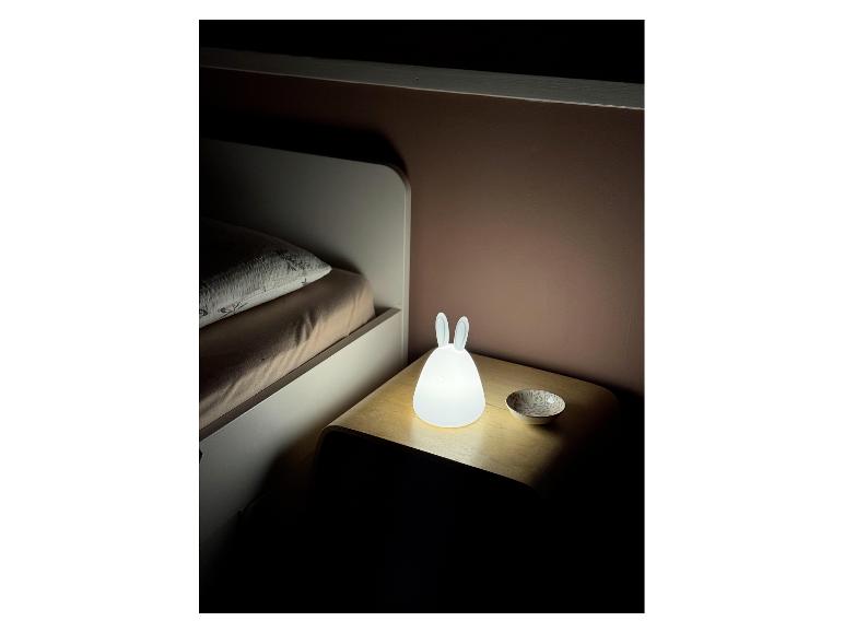 Hasenförmiges Nachtlicht auf einem Nachttisch neben einem Bett.
