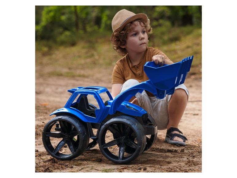 Junge spielt mit einem blauen Spielzeugtraktor im Wald.