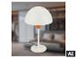 Weiße Tischlampe mit rundem Fuß und kuppelförmigem Schirm, in einem unscharfen Schlafzimmer.