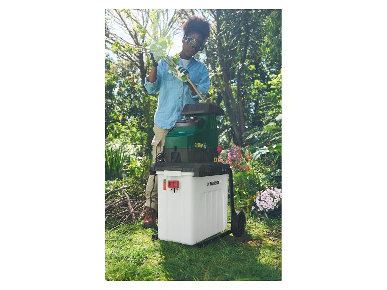 Frau im Garten benutzt einen Parkside Häcksler, um Äste zu zerkleinern.