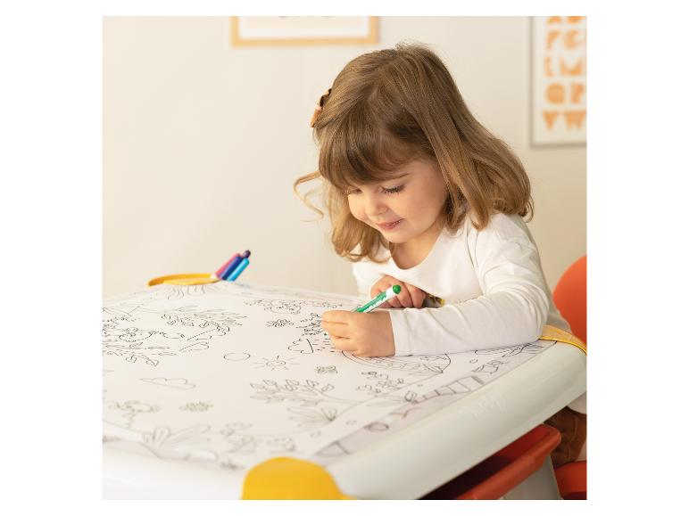 Kleines Mädchen malt ein Malbuch auf einem Tisch mit einem grünen Stift.