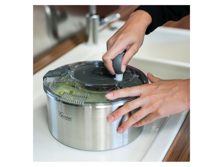 Eine Person benutzt eine Genius Salatschleuder zum Trocknen von Salat.