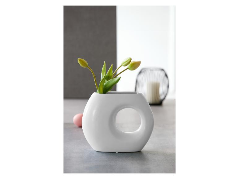 Eine weiße Vase mit modernem Design, gefüllt mit Tulpenknospen.