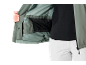 Person zeigt das Innere einer grünen Jacke mit schwarzem Unterhemd und weißer Hose.