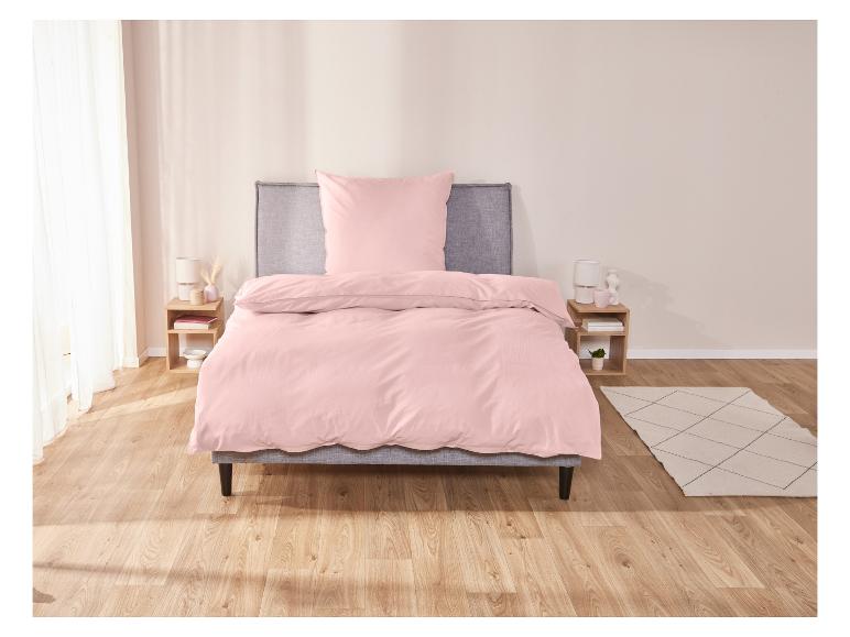 Ein rosafarbenes Bettbezug auf einem Bett in einem Schlafzimmer.