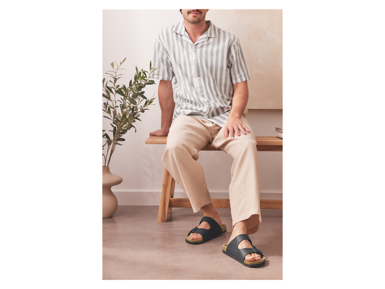 Mann in gestreiftem Hemd und Birkenstock-Sandalen.