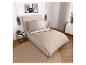 Schlafzimmer mit beigem Bett, Bettwäsche und rundem Teppich.