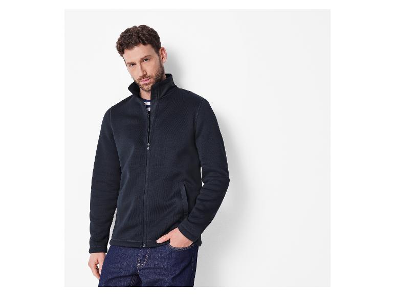 Mann in marineblauer Fleecejacke und blauer Jeans.