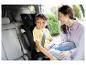 Lächelnde Mutter und Kind in einem Kindersitz im Auto.