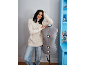 Lächelnde Frau in cremefarbenem Pullover und Jeans, posiert mit einer Schneiderpuppe.