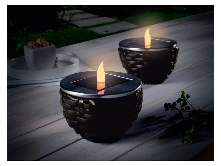 Zwei schwarze Solar-Kerzen auf einem Holztisch.