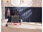 Badezimmer mit schwarzem Waschtisch, Toilette, floralem Teppich und marineblauer Paneelwand.