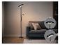 Schwarze Stehlampe mit Leselicht, neben einem grauen Sofa in einem Wohnzimmer.