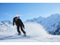 Snowboarderin mit Helm und Brille fährt die verschneiten Berge hinunter.