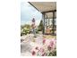 Frau reinigt Terrasse mit Hochdruckreiniger, umgeben von Pflanzen und einem modernen Haus.