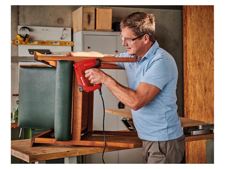 Mann polstert einen Stuhl in einer Werkstatt mit einem Elektrotacker.