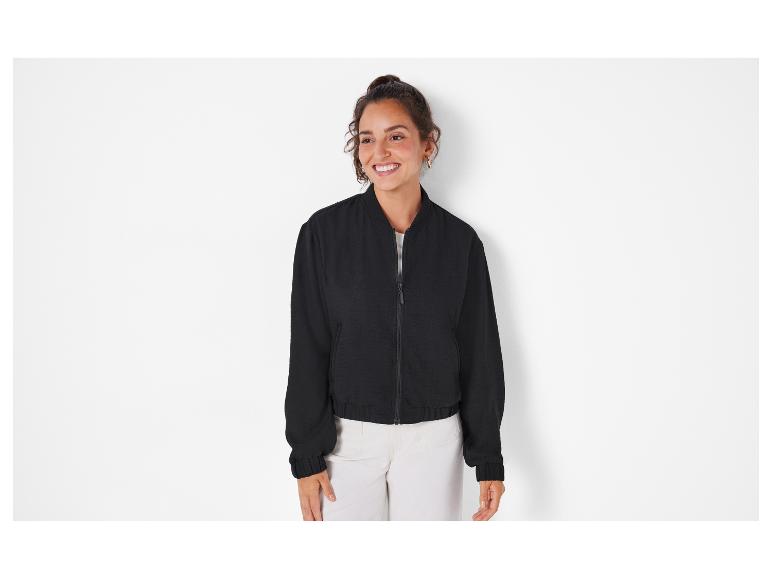 Eine Frau trägt eine schwarze Bomberjacke.