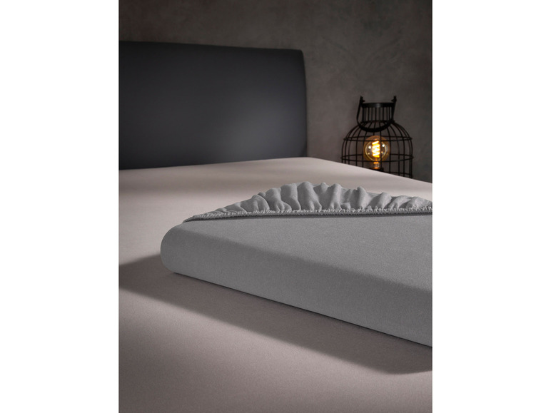 Ein graues Spannbettlaken auf einem Bett.