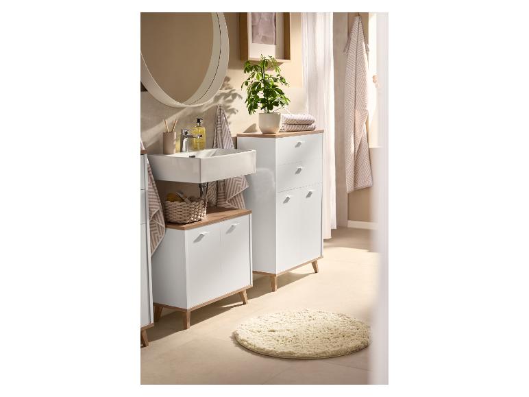 Badezimmer mit weißen Schränken, Holzplatten, Waschbecken und rundem Spiegel.