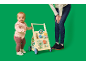 Baby mit Lauflernwagen und einer erwachsenen Person im Hintergrund