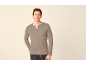 Mann trägt ein graubeiges Langarm-Henley-Shirt und dunkle Jeans.