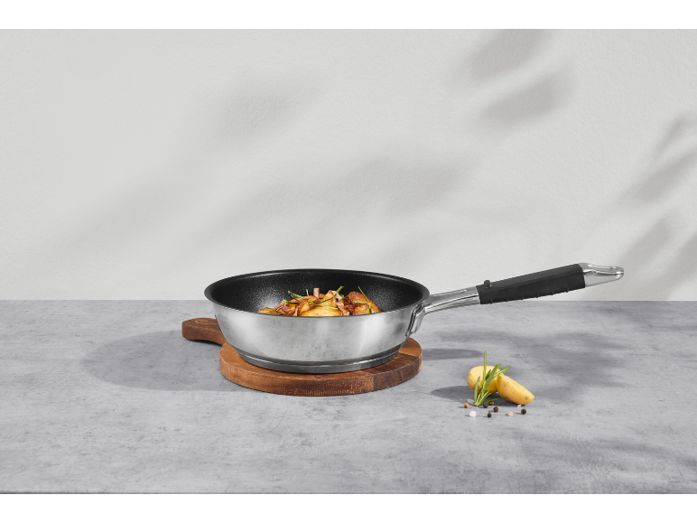 Bratpfanne mit Bratkartoffeln und Rosmarin auf einem Holzschneidebrett.