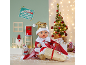 Babypuppe im Weihnachtskostüm mit Geschenksack vor festlichem Hintergrund.