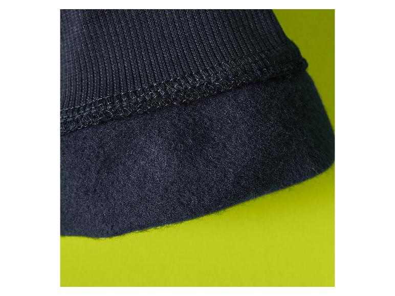 Detail aus schwarzem Fleece und Rippstoff mit Naht auf limettengrünem Hintergrund.