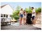 Drei Freunde grillen draußen auf einer Terrasse mit Gartenmöbeln.
