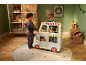 Zwei Kinder spielen mit einem Spielzeug-Foodtruck in einem weihnachtlich dekorierten Zimmer.
