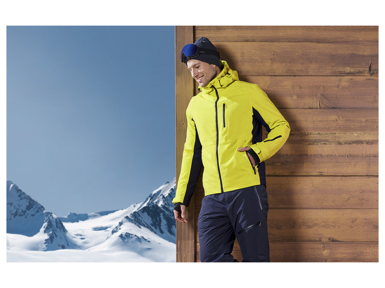 Mann in gelber Skijacke und blauer Skihose